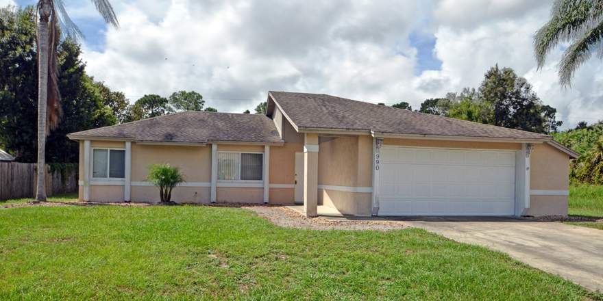 Outdoor view of home with palm tree and garage